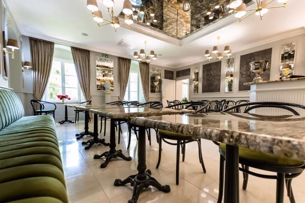 Jasna i elegancka sala restauracyjna Dworu w Żytnie z marmurowymi stołami i stylowym wystrojem.