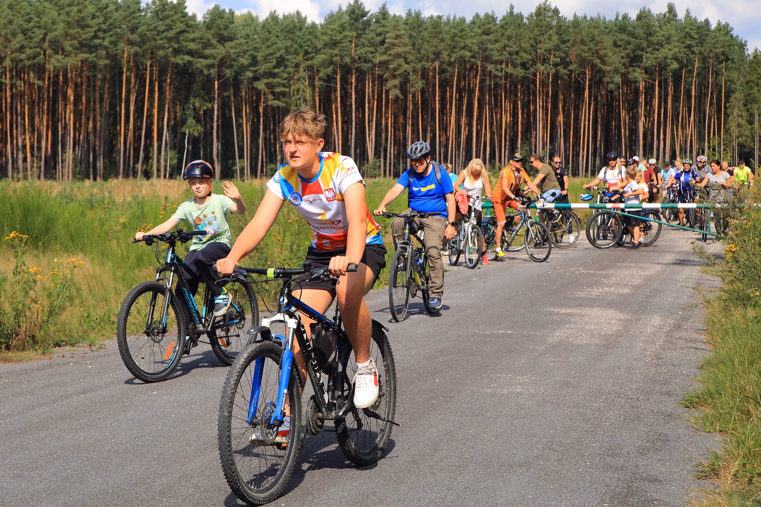 Grupa rowerzystów jedzie leśną drogą