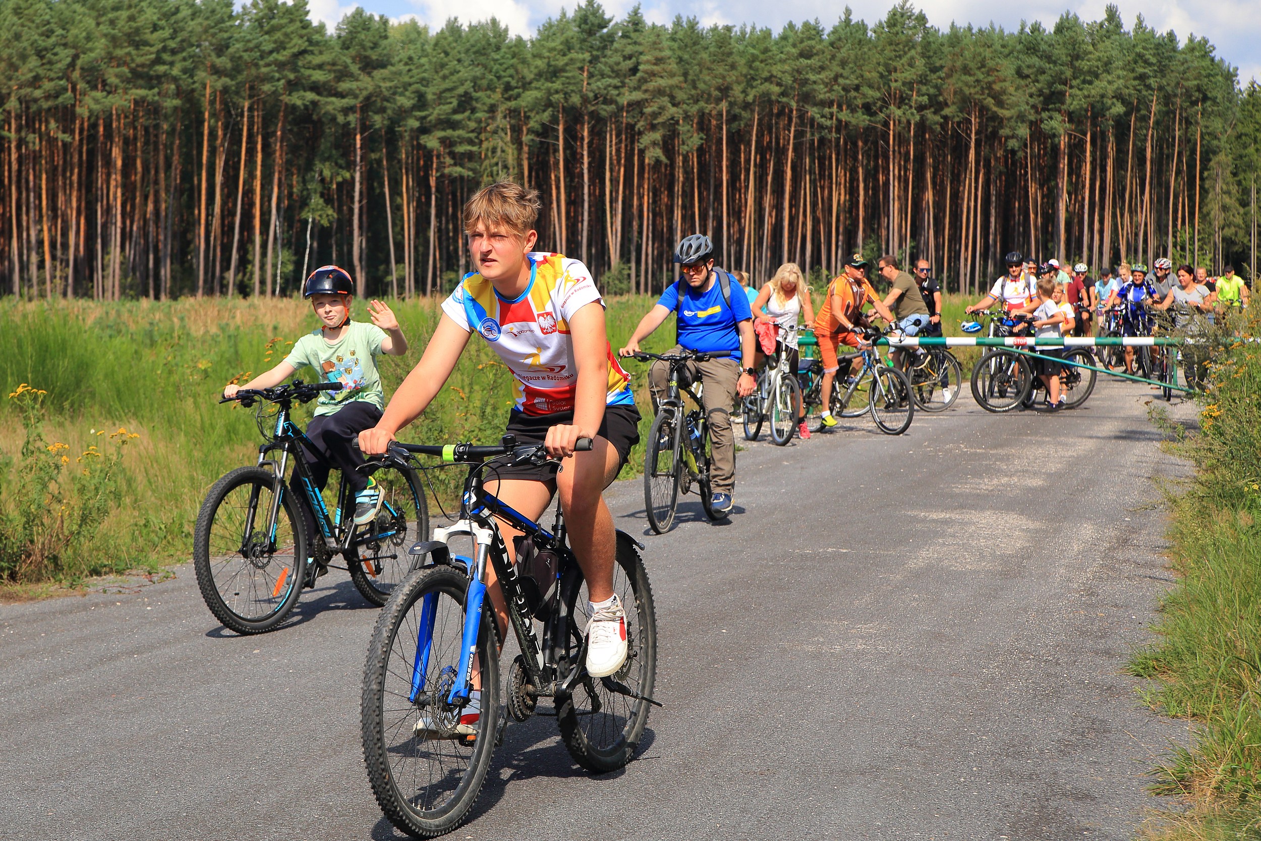 Grupa rowerzystów jedzie leśną drogą