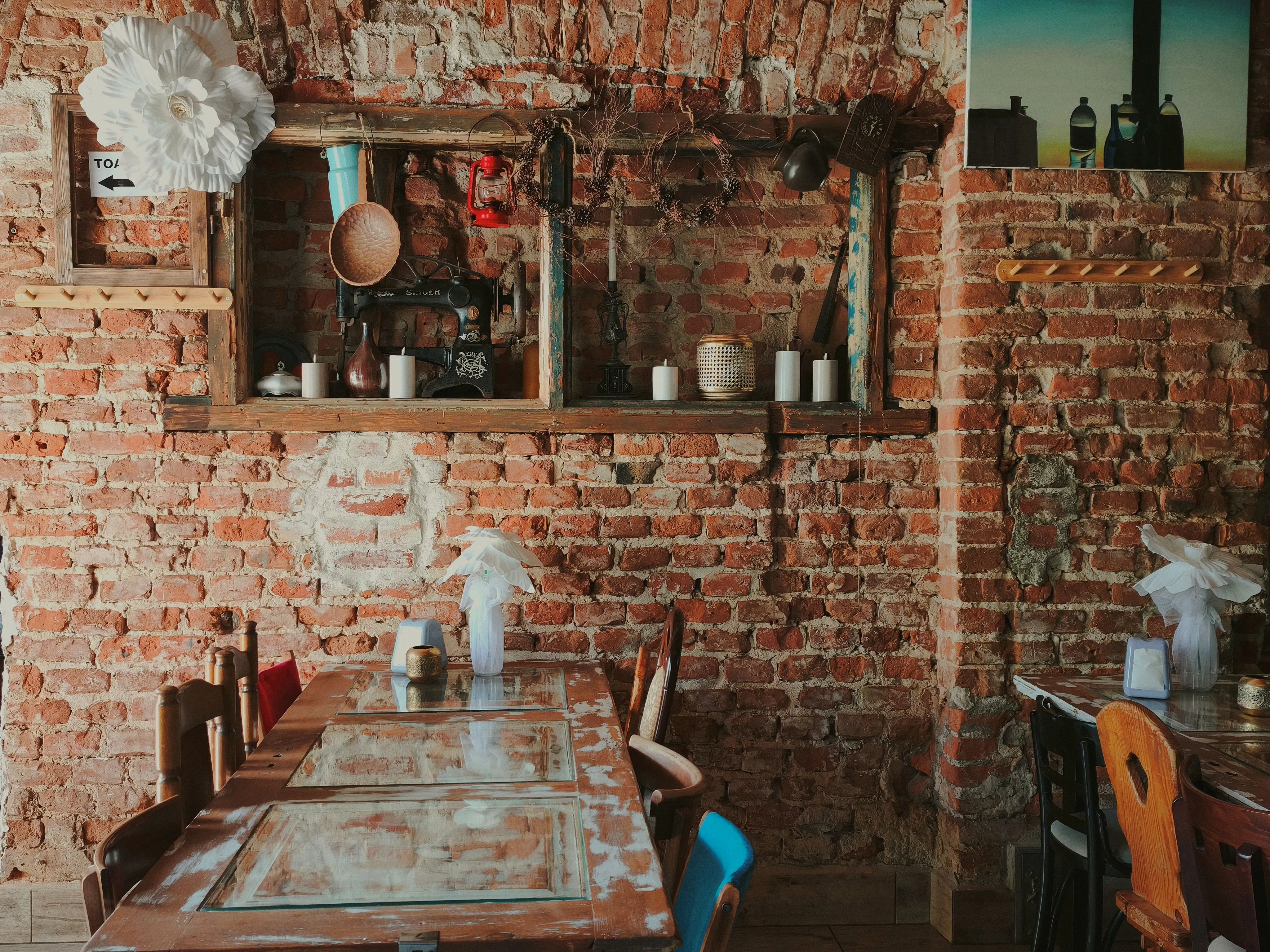 Rustykalne wnętrze Baru Strzecha z ceglaną ścianą, drewnianymi stołami oraz oryginalnymi dekoracjami nawiązującymi do tradycyjnego wystroju.