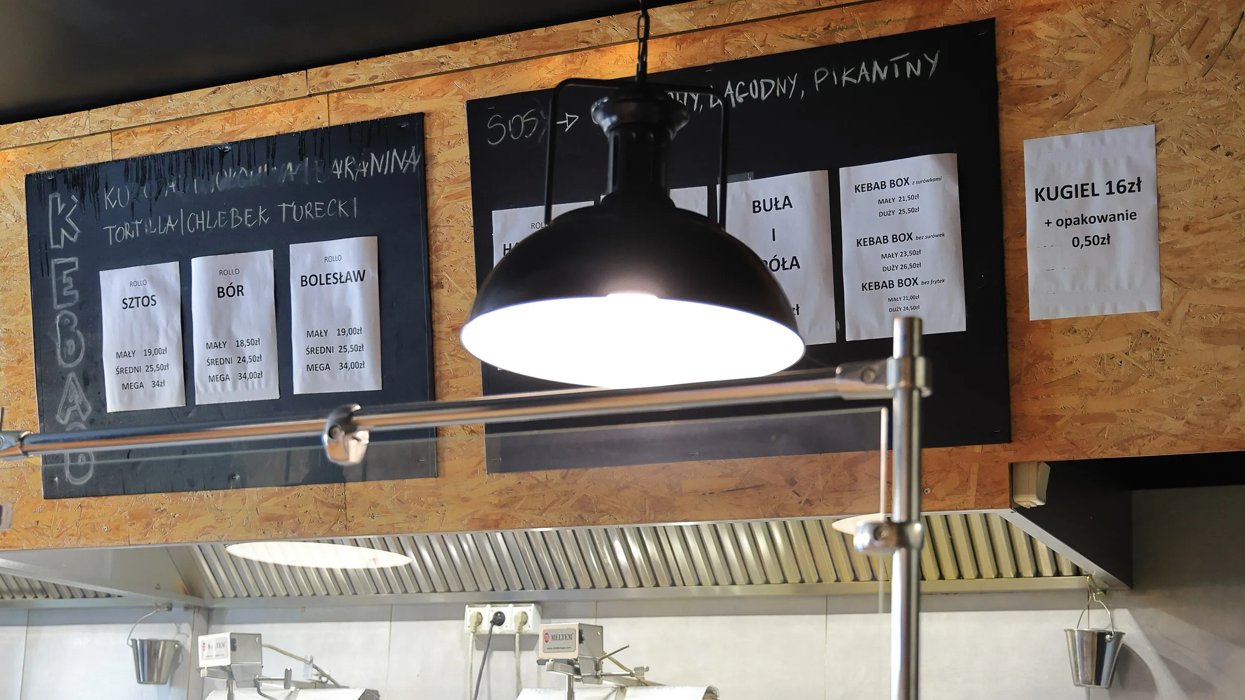 aplecze gastronomiczne restauracji Sztos Mięso w Przedborzu z widocznym menu kebabów, rollo i kugla oraz otwartą kuchnią.