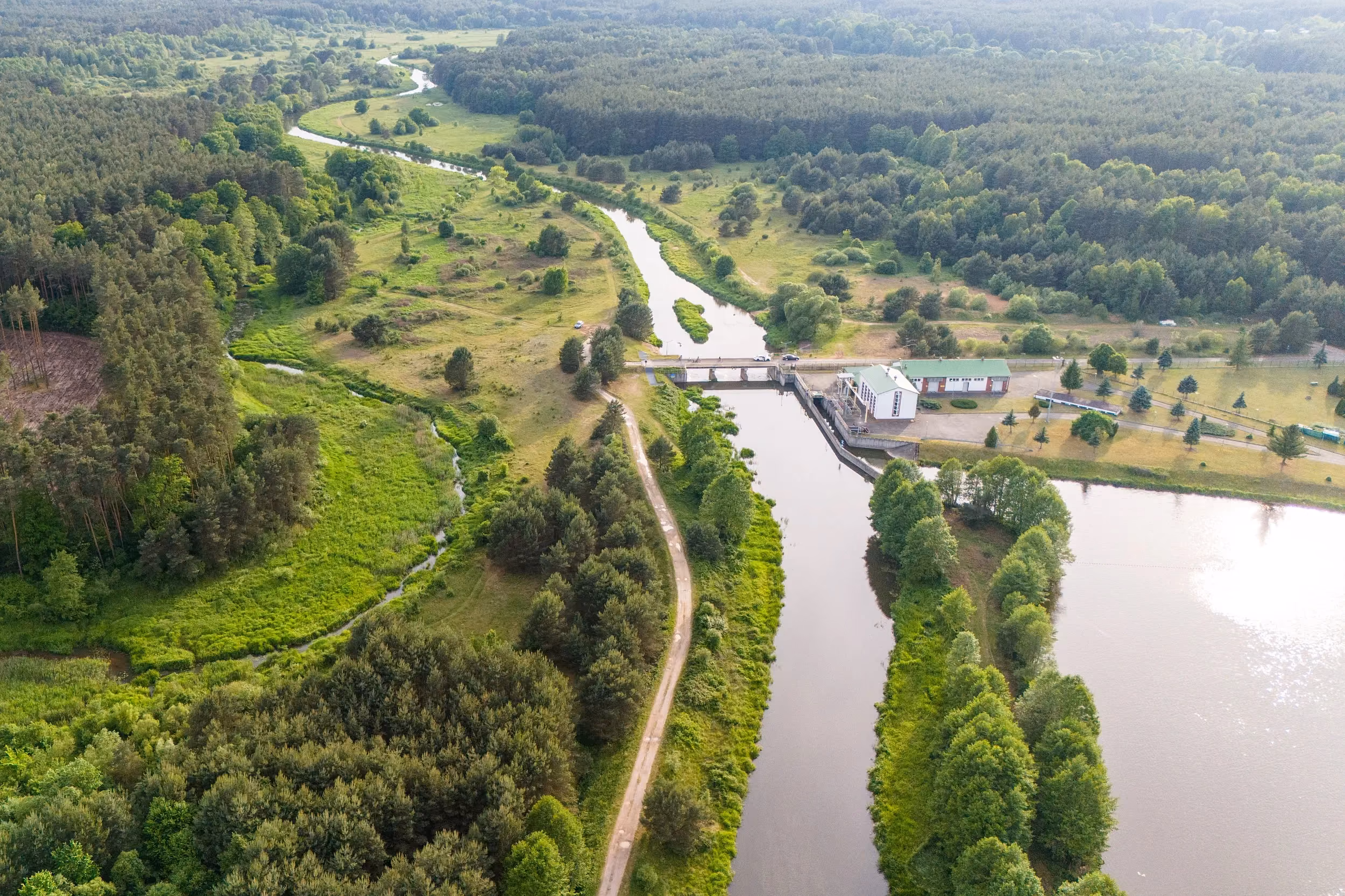 Widok z lotu ptaka na zbiornik oraz urządzenia hydrotechniczne w Zakrzówku Szlacheckim. Wokół rozciągają się lasy, łąki i dolina rzeki Warty