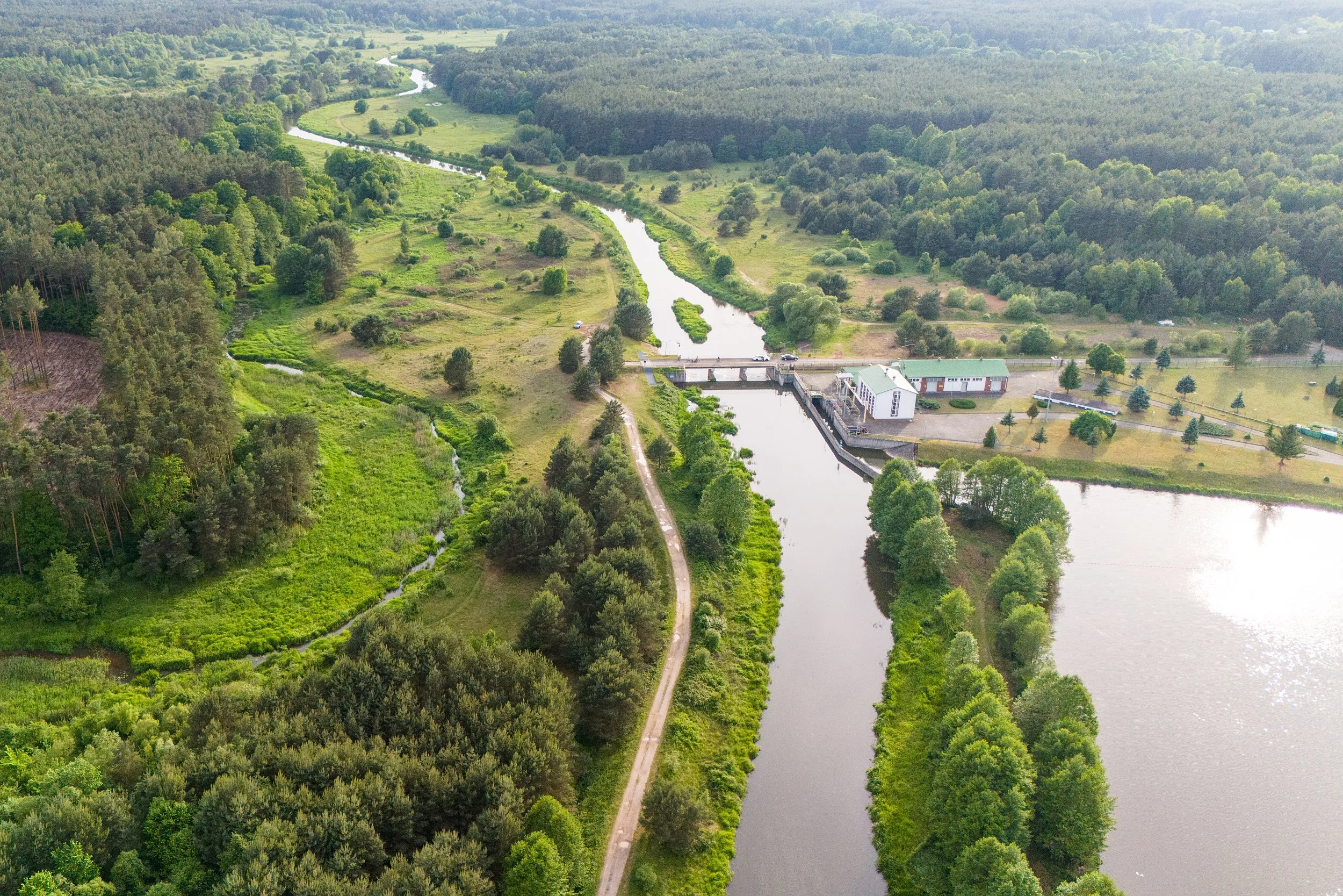 Widok z lotu ptaka na zbiornik oraz urządzenia hydrotechniczne w Zakrzówku Szlacheckim. Wokół rozciągają się lasy, łąki i dolina rzeki Warty