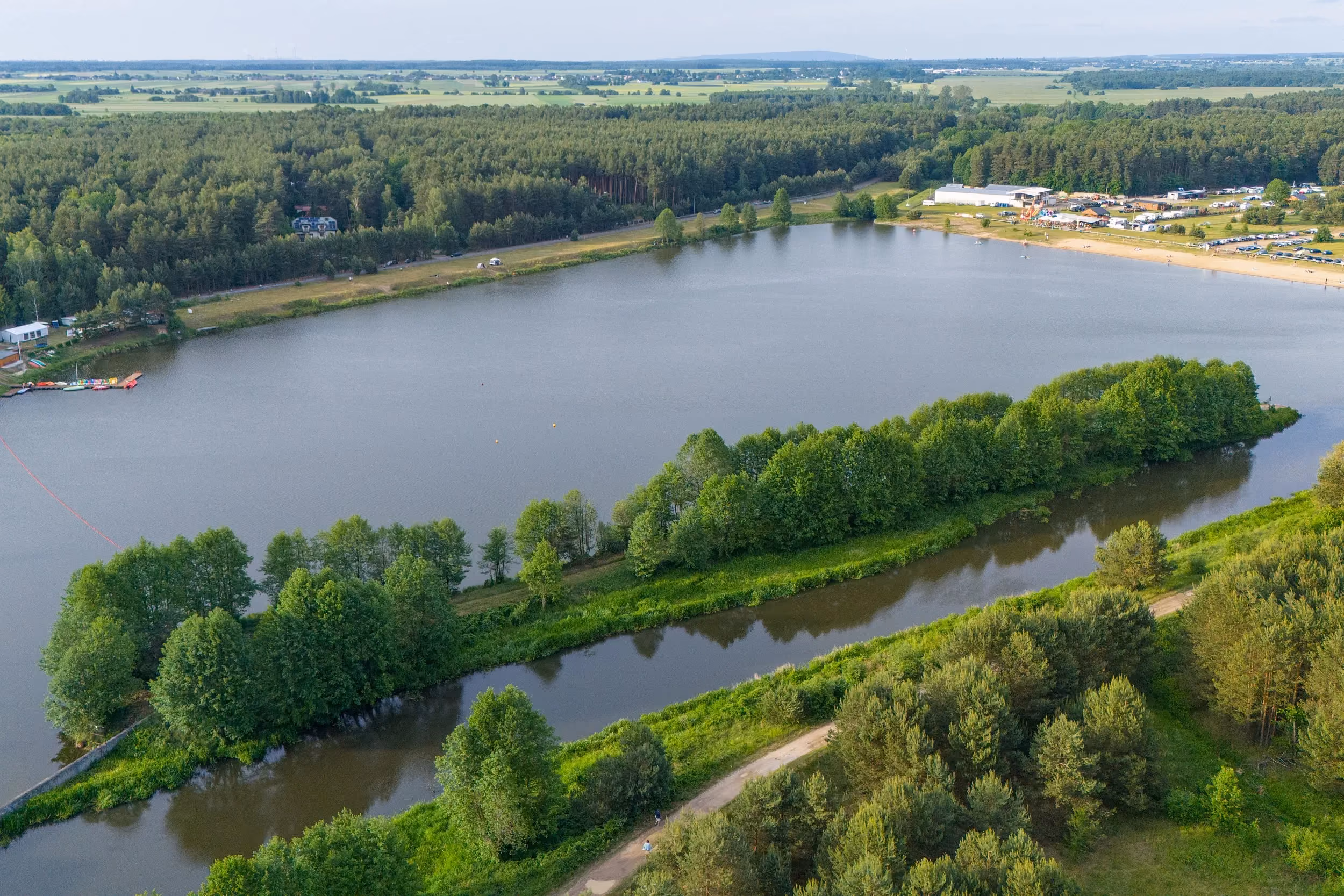 Widok lotniczy zbiornika w Zakrzówku Szlacheckim otoczonego lasami. Na pierwszym planie widoczny kanał wodny i droga, w tle plaża oraz teren rekreacyjny.