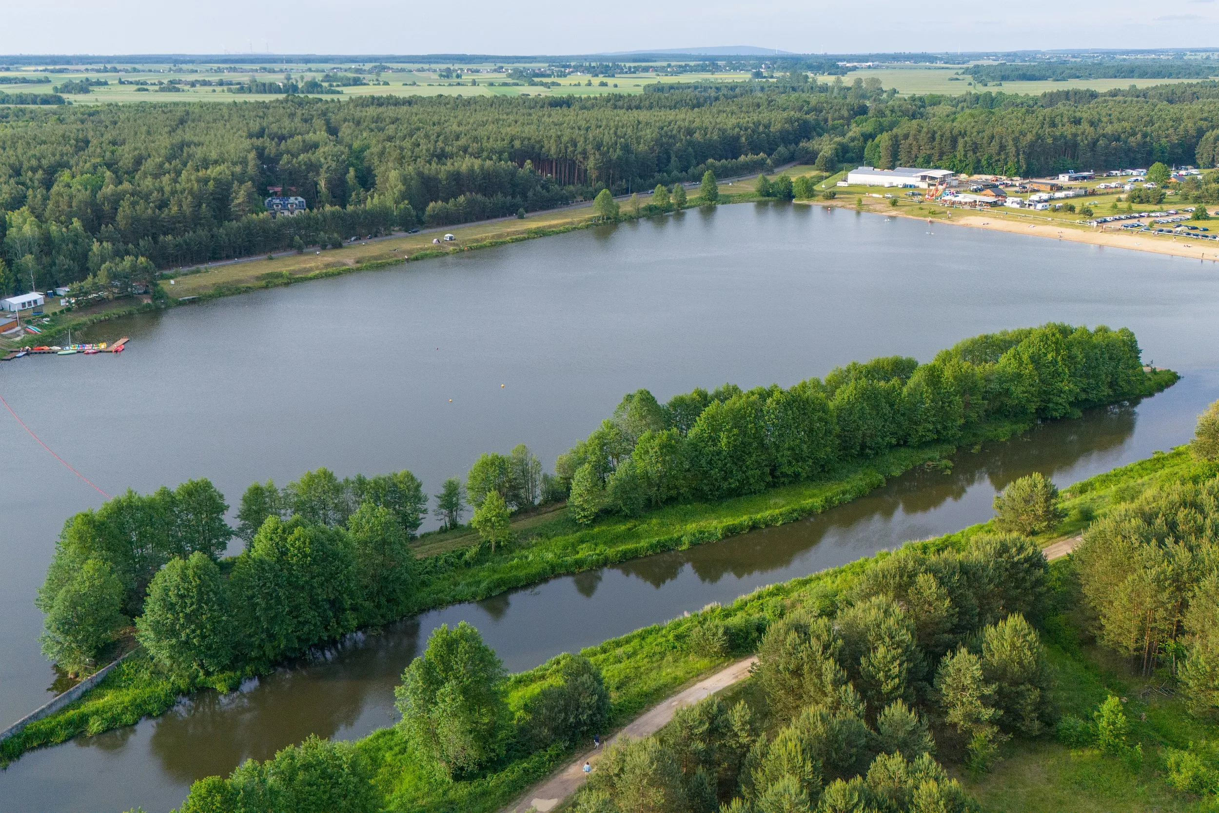 Widok lotniczy zbiornika w Zakrzówku Szlacheckim otoczonego lasami. Na pierwszym planie widoczny kanał wodny i droga, w tle plaża oraz teren rekreacyjny.