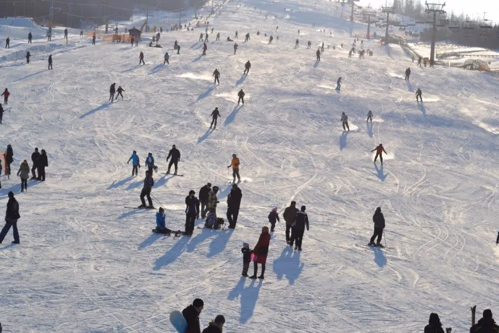 Narciarze i snowboardziści korzystający z szerokiej trasy narciarskiej na Górze Kamieńsk, największym stoku w centralnej Polsce.