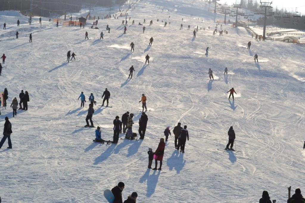 Narciarze i snowboardziści korzystający z szerokiej trasy narciarskiej na Górze Kamieńsk, największym stoku w centralnej Polsce.