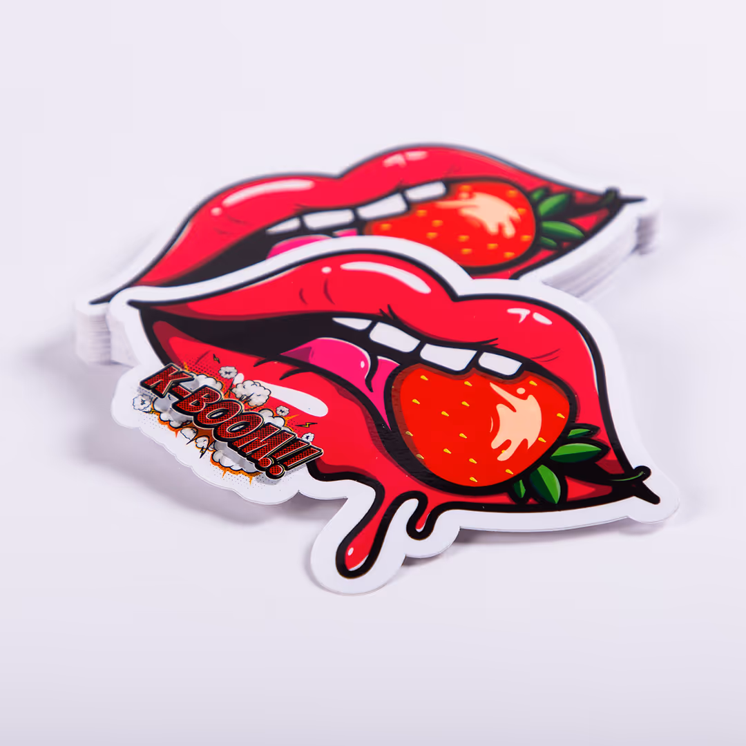 Sticker met felrode lippen die een aardbei vasthouden en de tekst 'K-BOOM!!' in stripstijl.