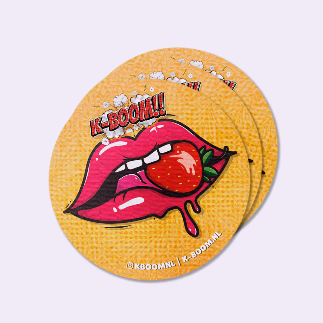 Ronde sticker met roze lippen die een aardbei vasthouden en tekst 'K-BOOM!!' op een geel patroonachtergrond.