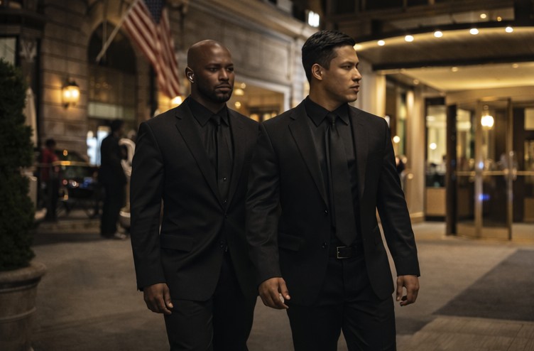 Two security guards walking outside a luxurious hotel at night.