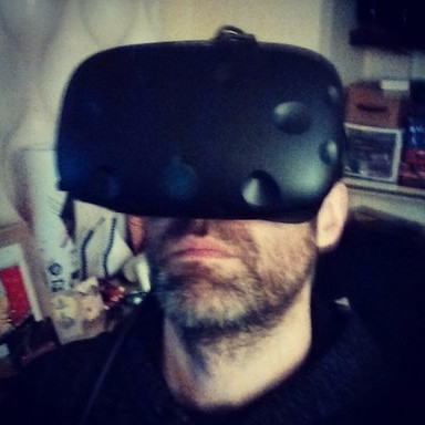 Man wearing a black virtual reality headset indoors with shelves and objects in the background.