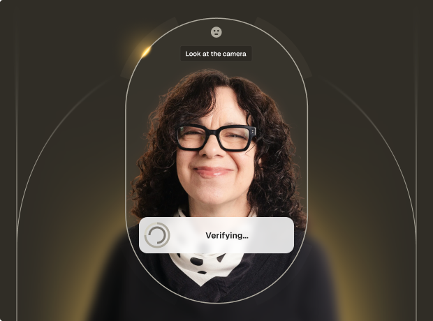 Woman with curly hair and glasses smiling, engaging in a facial verification process on a digital interface.
