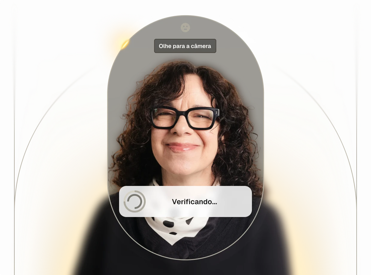 Woman with curly hair and glasses smiling while a facial recognition app verifies her identity on a smartphone screen.