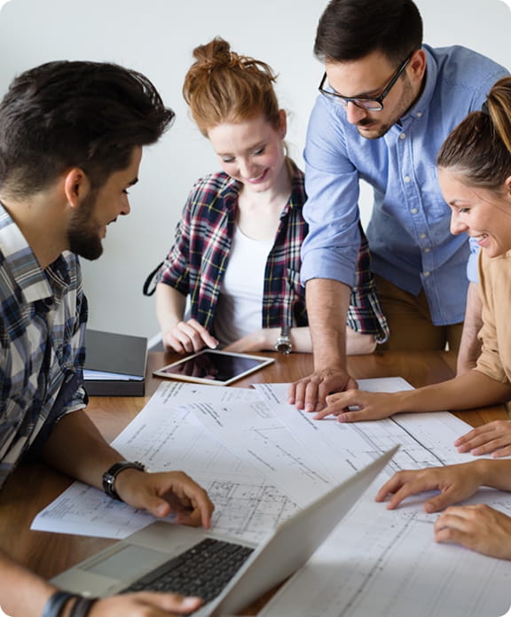 Équipe projet collaborant autour de plans techniques pour concevoir et piloter un projet de digitalisation.