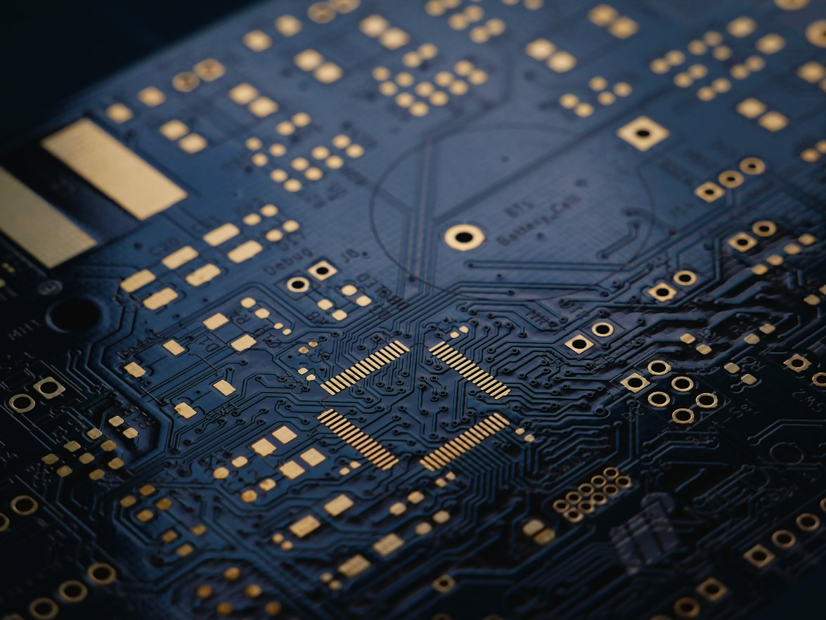 Close-up of a black printed circuit board with gold connectors and intricate circuitry patterns.