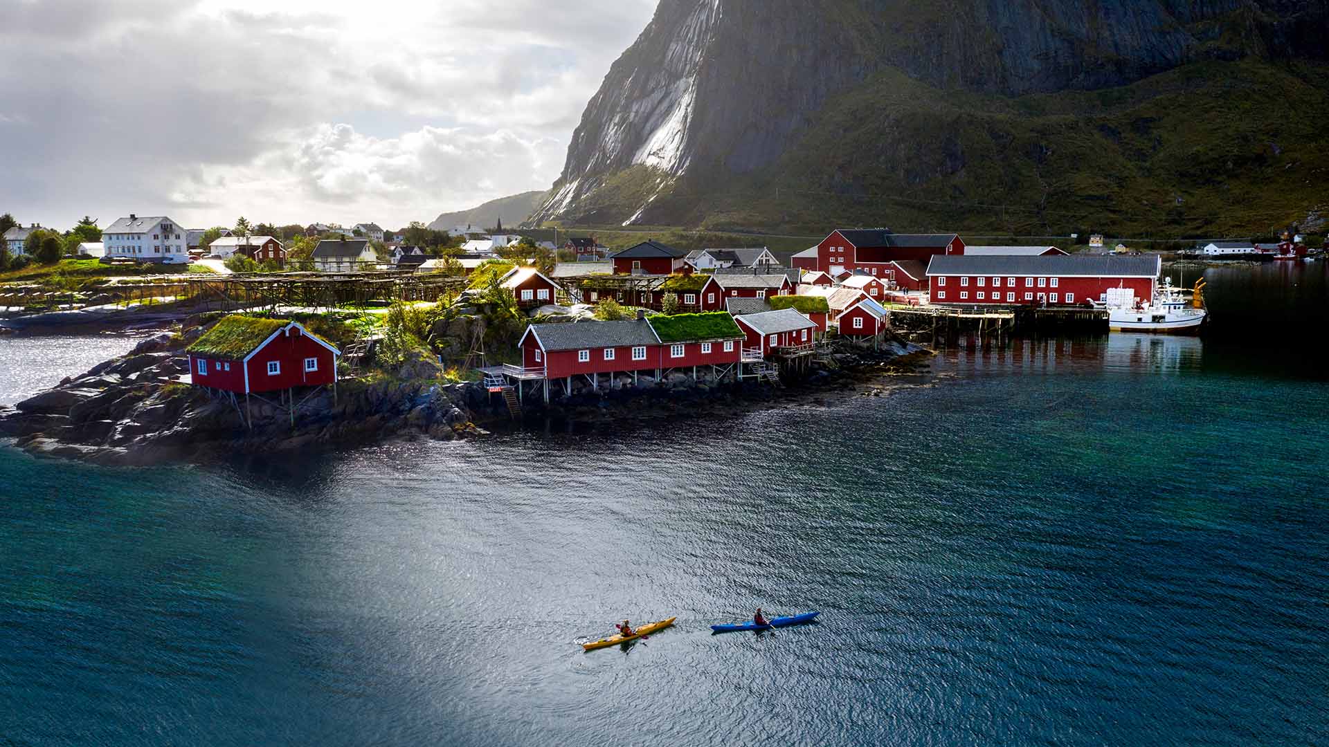 Aerial view of a lush coastal town with a mountain looming in the background.