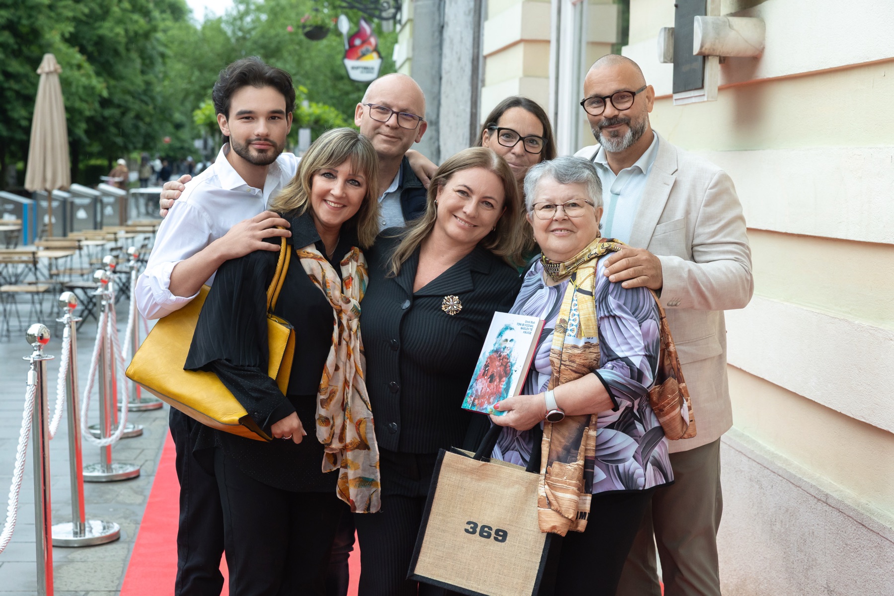 Skupinska fotografija gostov pred rdečo preprogo po predstavitvi knjige »Toni bi poznal naslov te knjige«