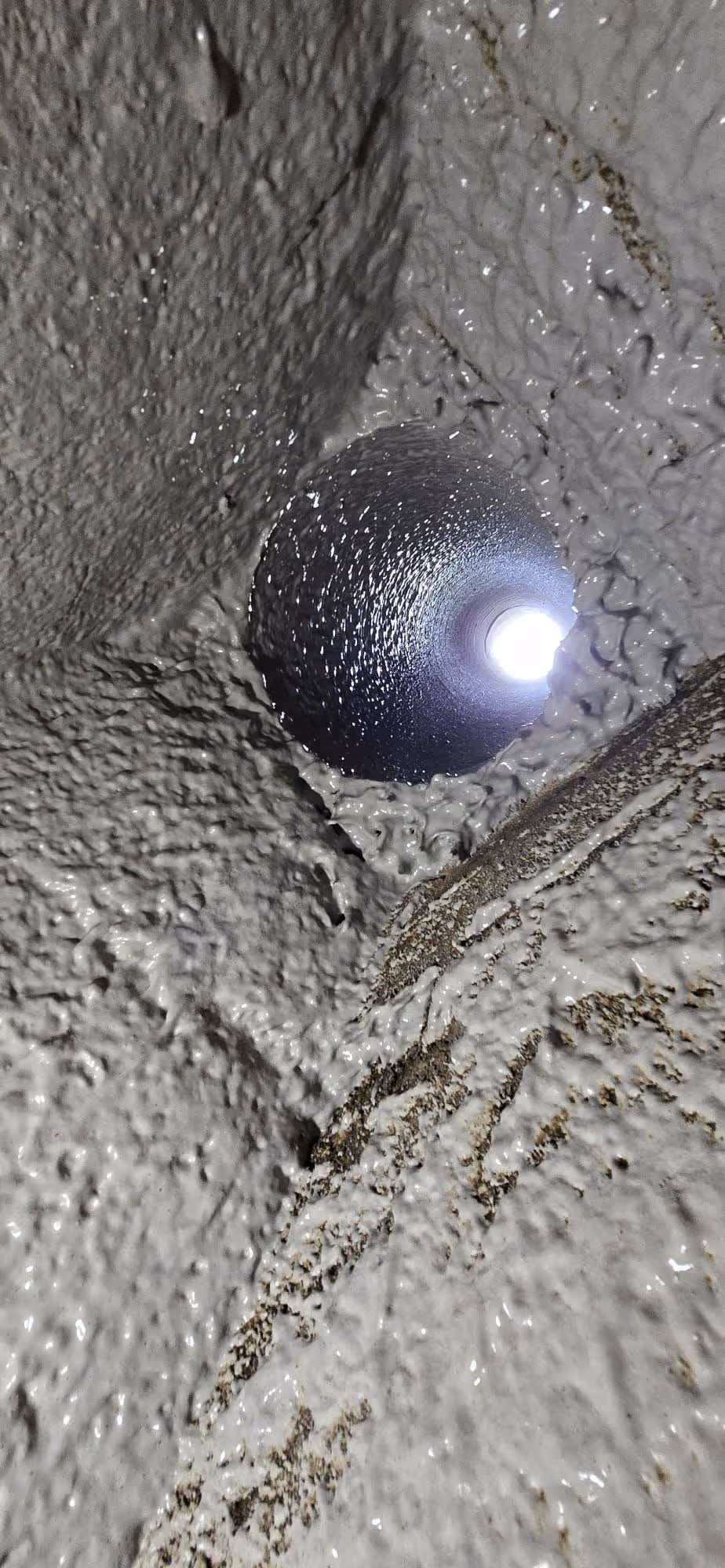 Close-up view inside a textured, gray pipe or tunnel with light visible at the far end.