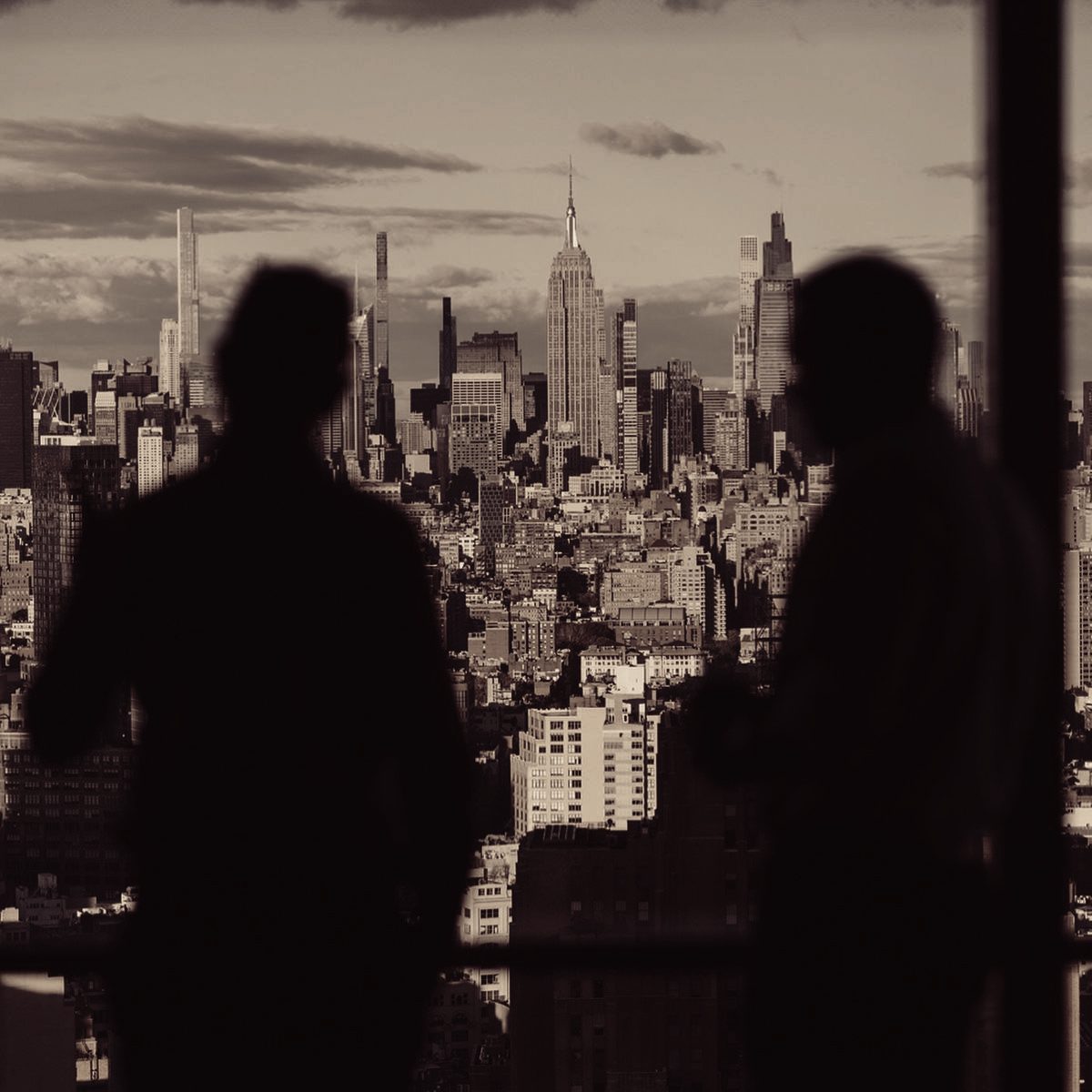 Two business leaders in silhouette in conversation above a city skyline