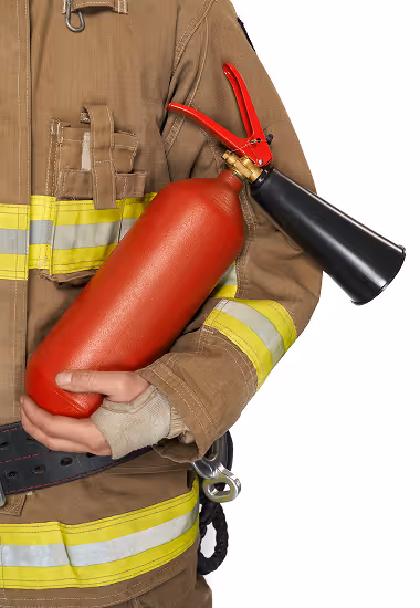 Person dressed in firefighter gear holding a red fire extinguisher with a black nozzle.