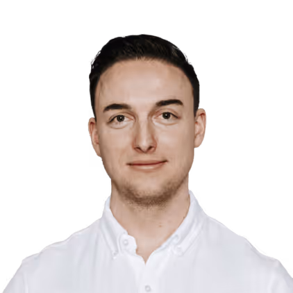 Porträt eines jungen Mannes mit kurzen dunklen Haaren, der ein weißes Hemd trägt und in die Kamera lächelt.