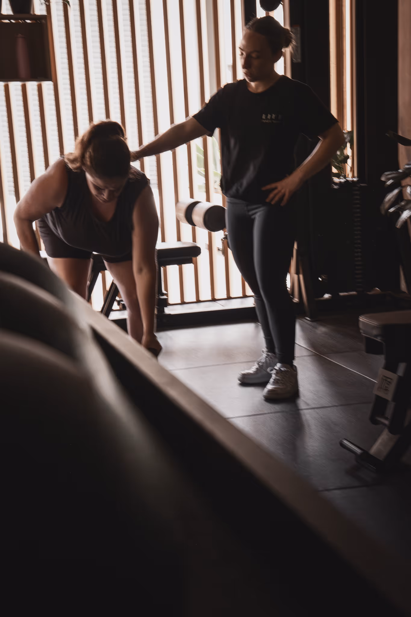 Client doing assisted dips on parallel bars with a trainer supervising