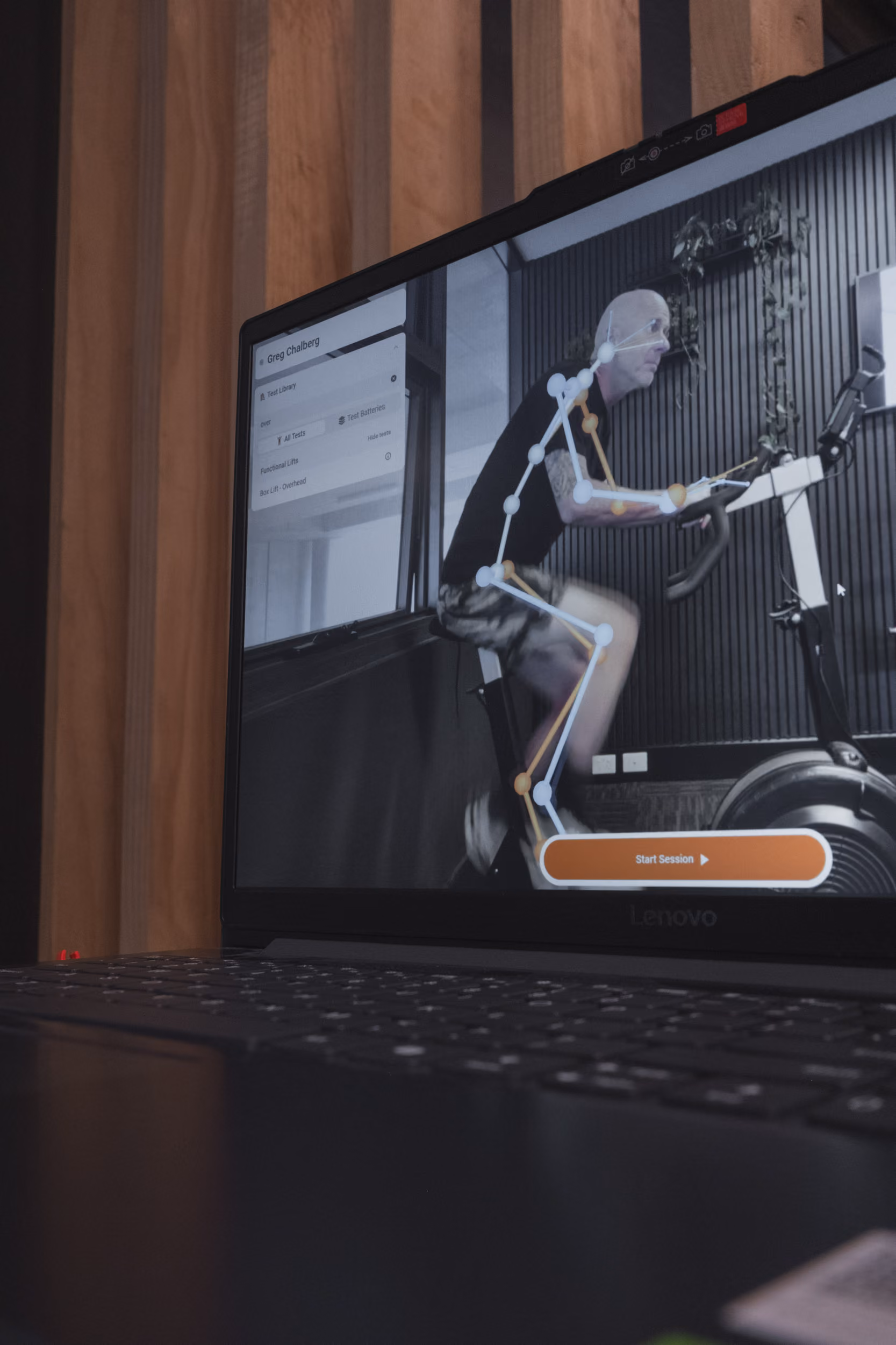 Computer screen shows a skeletal overlay on a man exercising on a stationary bike with a Start Session button.