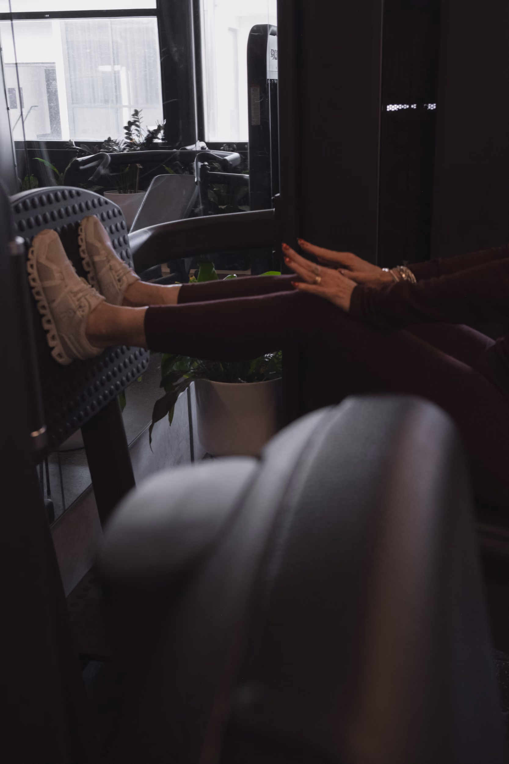 Person using leg press gym machine wearing white sneakers and dark workout pants.