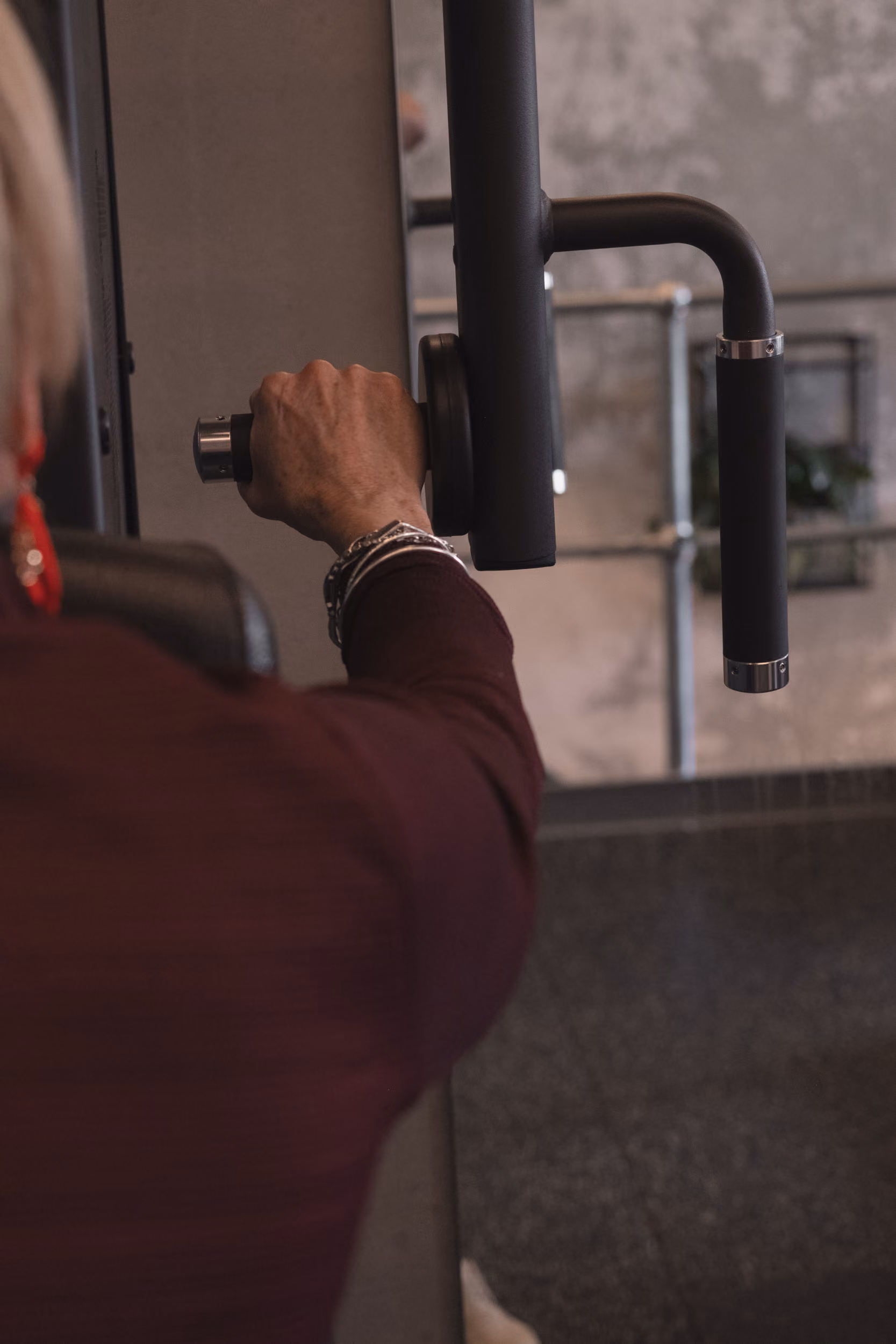 Close-up of a person gripping a black exercise machine handle at a gym.