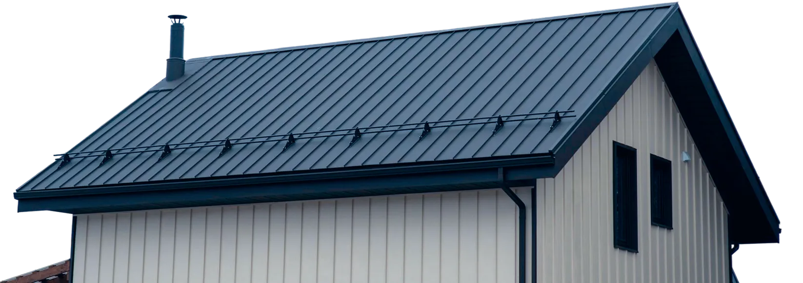 Modern house roof with metal panels, black chimney, and vertical siding on the walls.