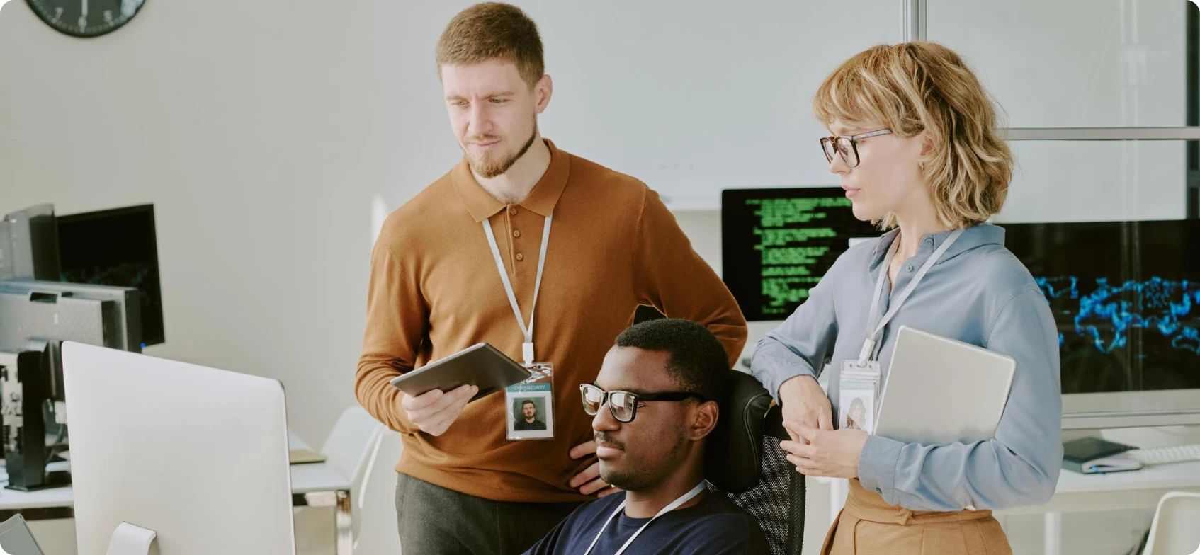 Three coworkers conversing in a modern office at night, each holding a coffee mug.