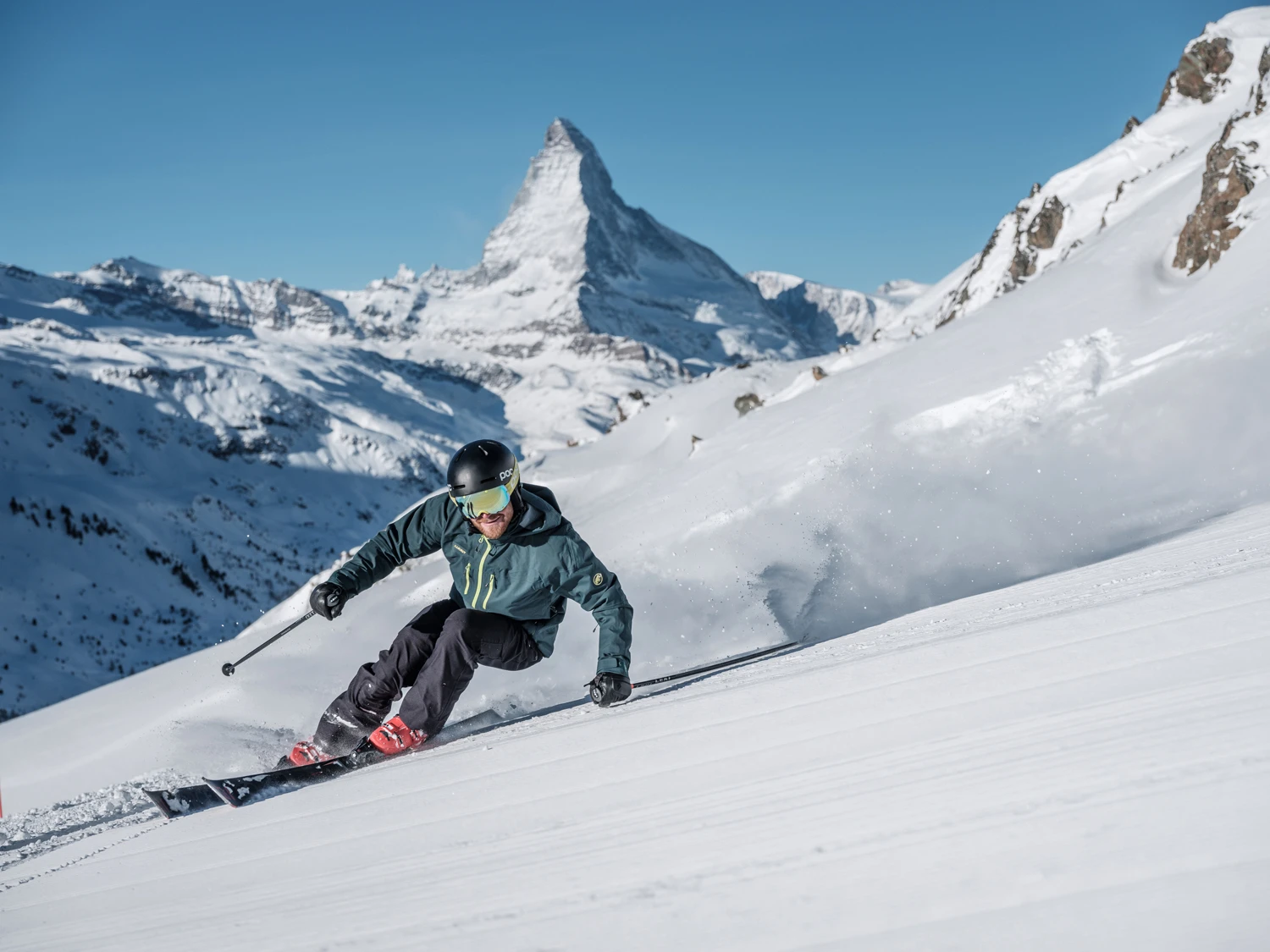 Skifahrer an einem sonnigen Wintertag auf der Skipiste in Zermatt mit dem Matterhorn m Hintergrund.
