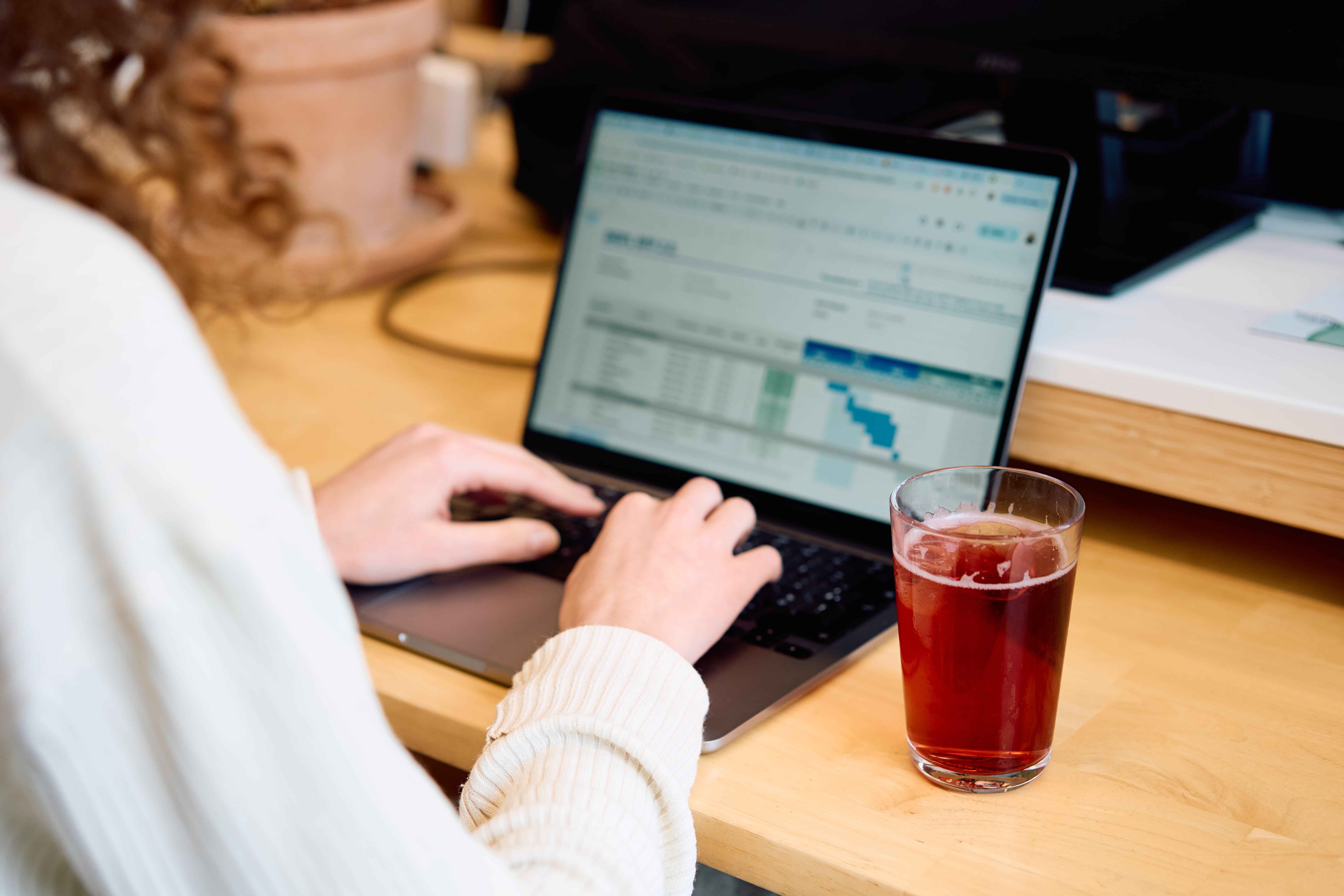 Kantoormedewerker werkt met een Dripl-drankje naast zich op het bureau