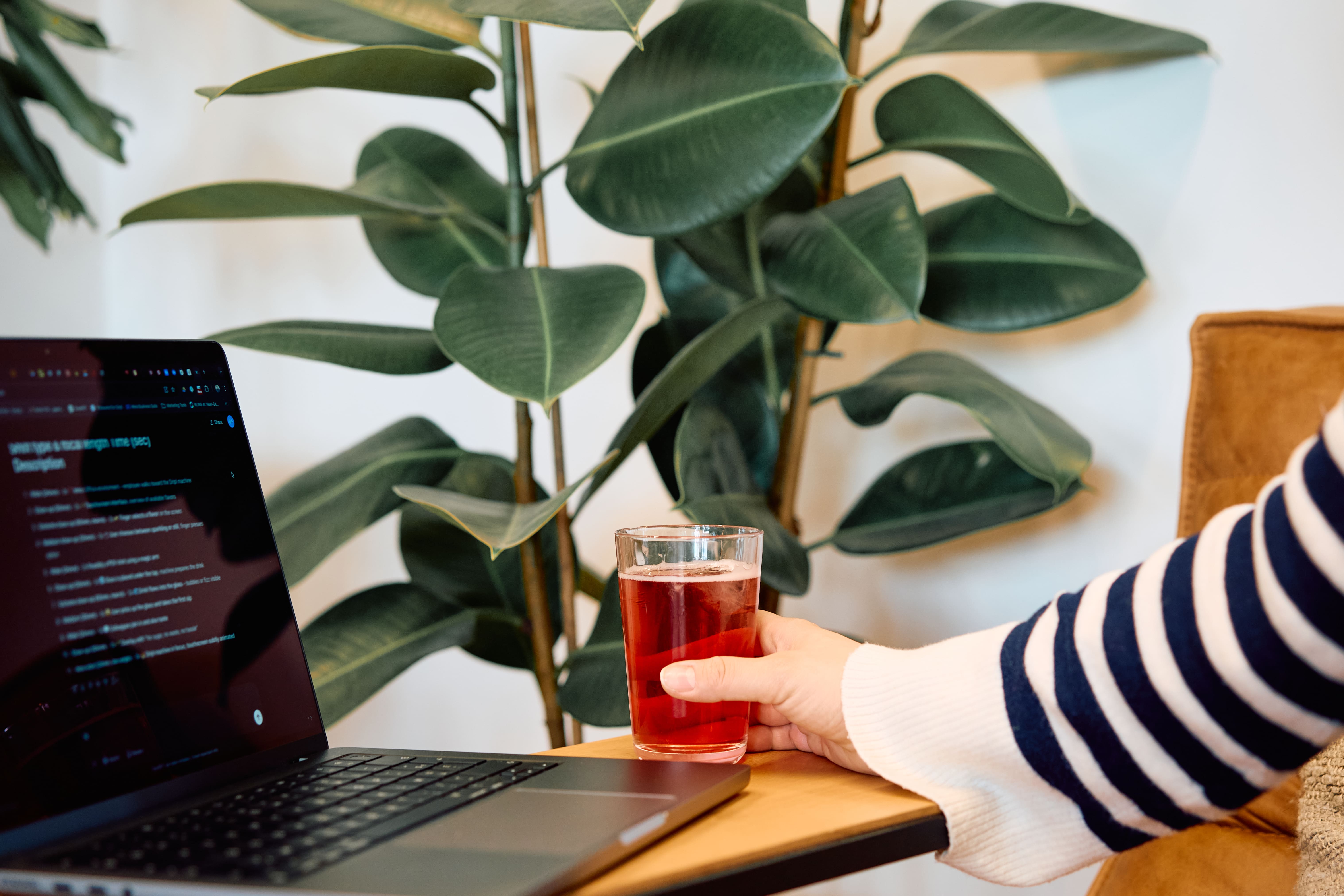 Vrouw werkt aan haar bureau met een Dripl drink naast haar laptop, gezond hydratatie-alternatief op kantoor
