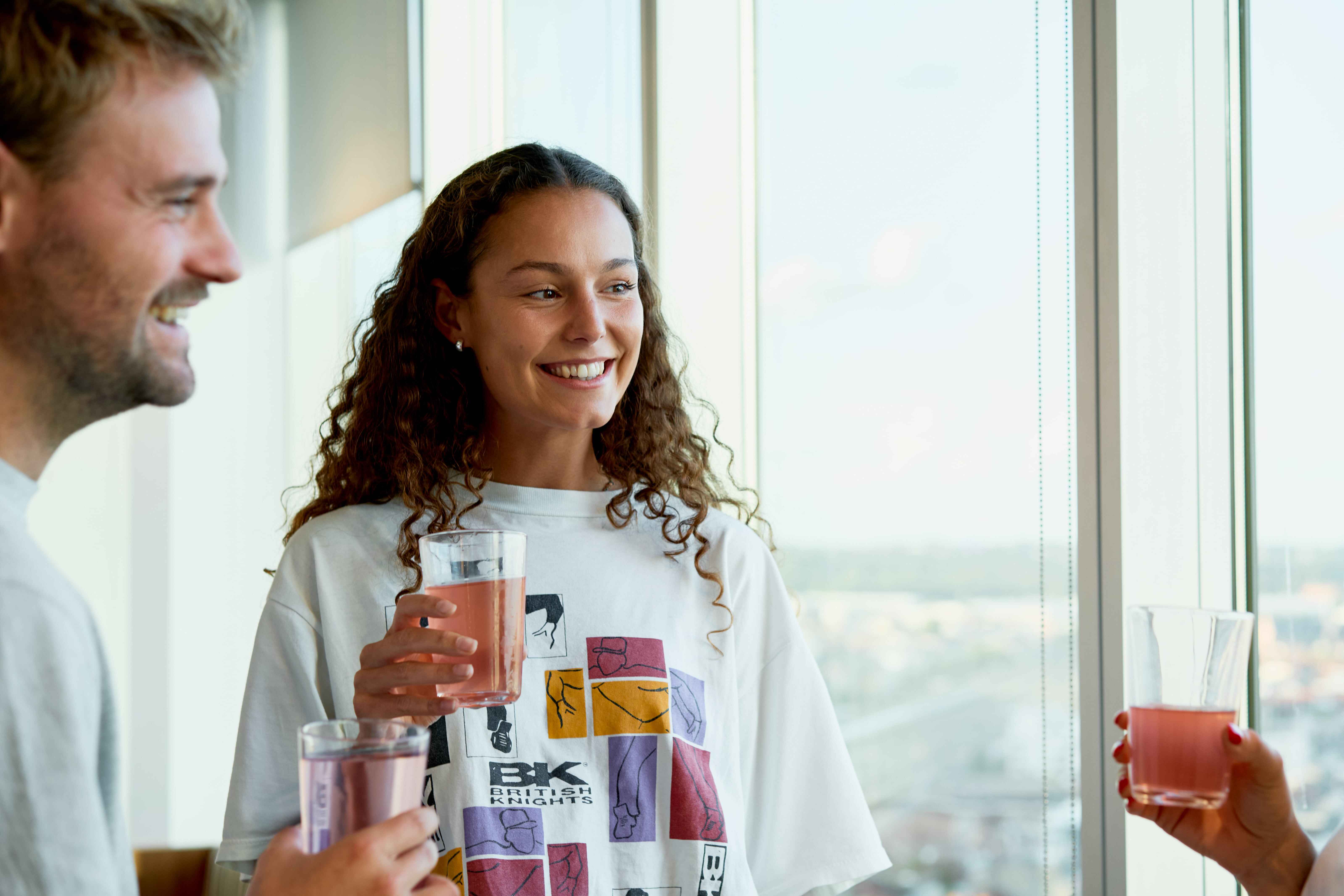 Lachende medewerker met een glas gevuld met een Dripl Drink.