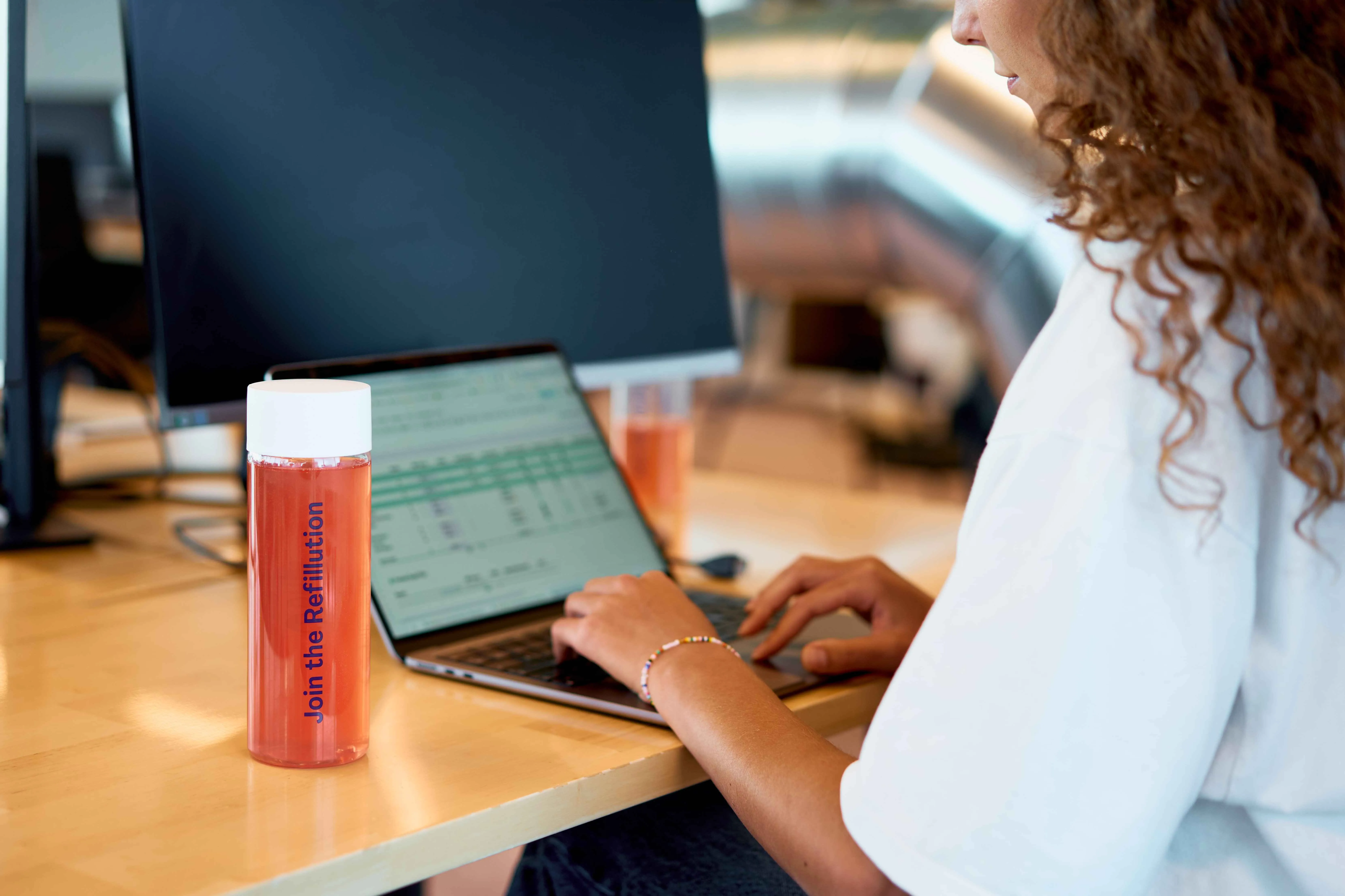 Employee at a desk with a reusable Dripl bottle filled with flavored water.