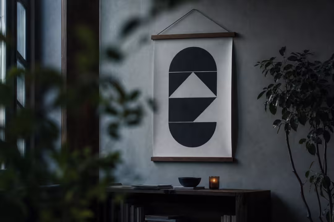 Hanging canvas wall art featuring geometric black and white shapes in a moody room interior.