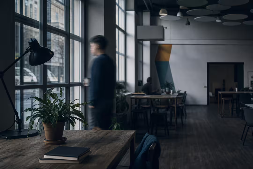 Interior of One Globe Coworking space with large windows and a wooden desk in the foreground.