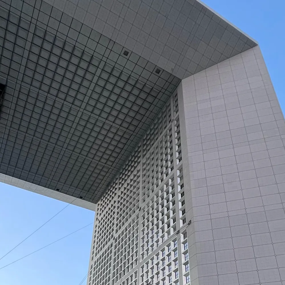 Upward view of Tetmet France office building with a grid-like structure under a clear blue sky.