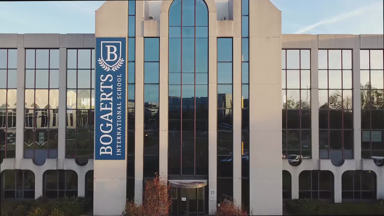Front view of Bogart's International School building with large glass windows and a blue vertical sign.
