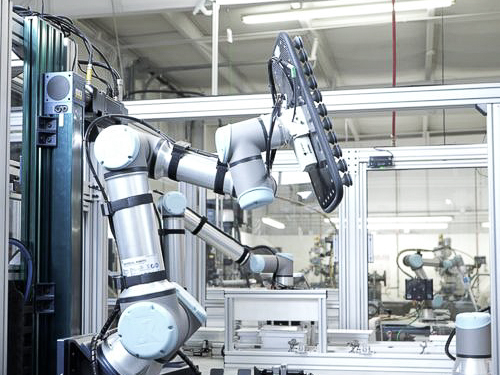 Aseptic isolator with white gloves attached, used for sterile pharmaceutical filling, with a reflection of a person working on a computer behind the glass.