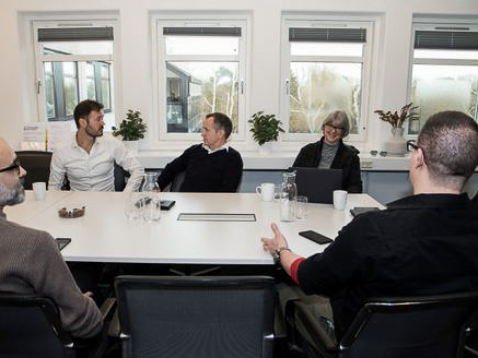 Aseptic isolator with white gloves attached, used for sterile pharmaceutical filling, with a reflection of a person working on a computer behind the glass.