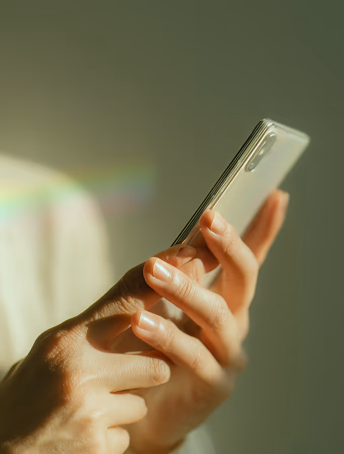Person holding and using a modern smartphone with a clear case against a softly lit background.