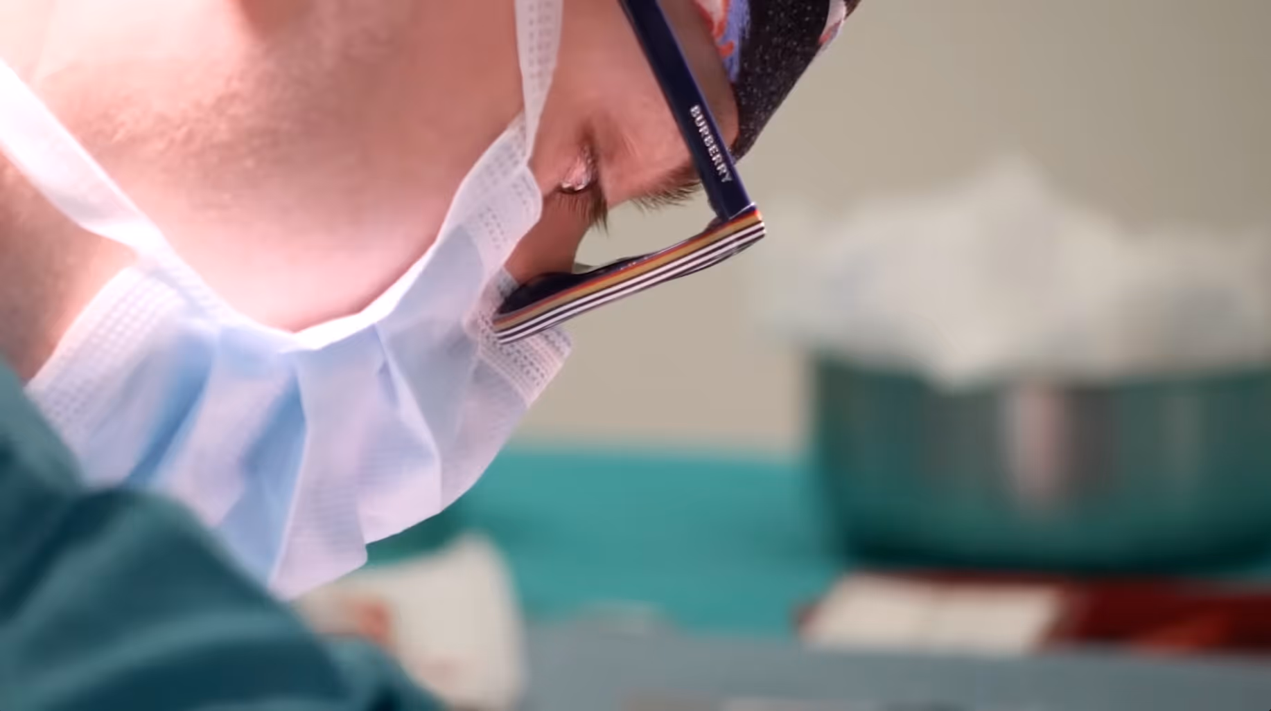 Close-up of a person wearing a surgical mask and glasses, focused on medical work.