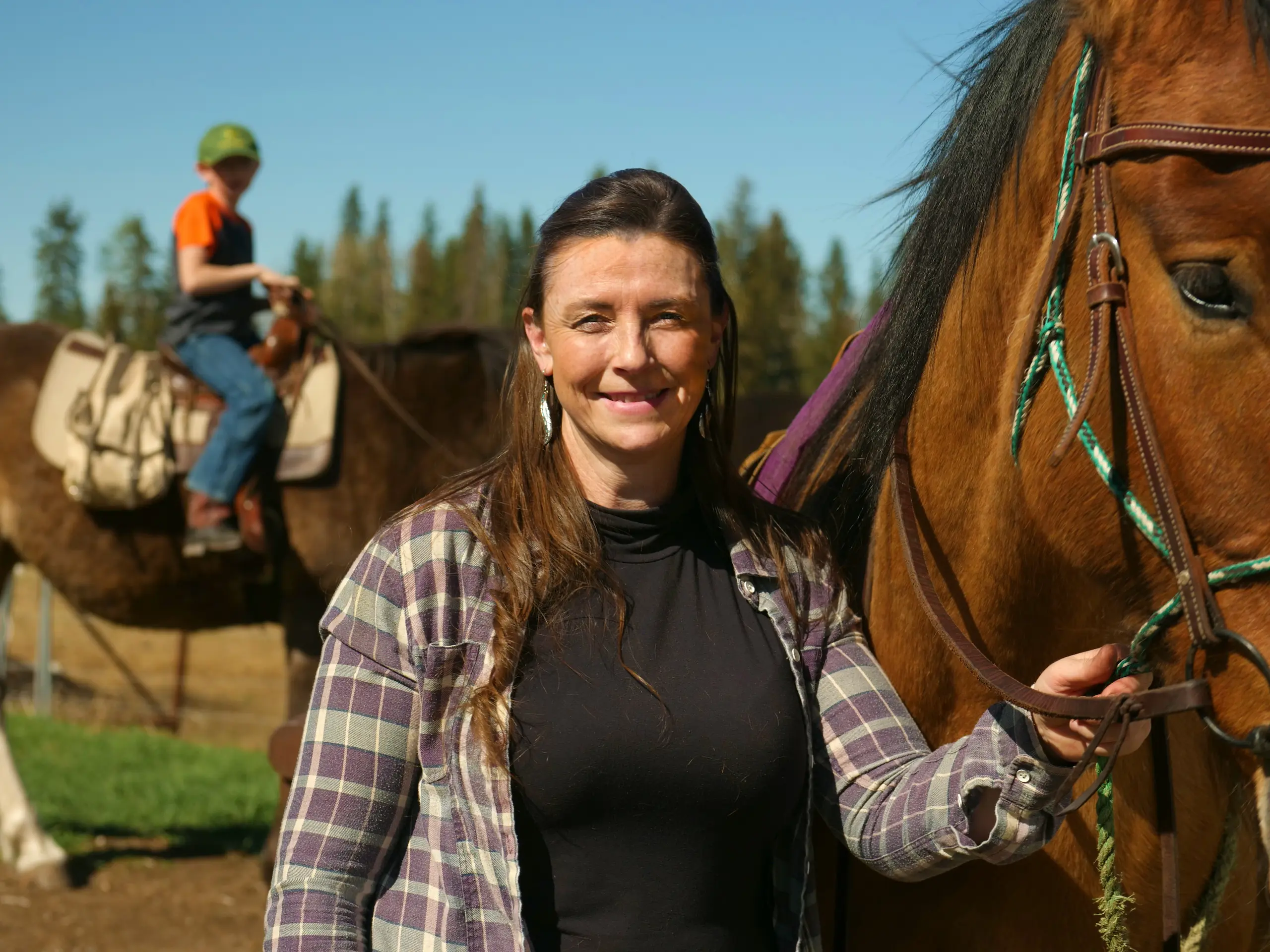 A woman smiles holding onto a horses reigns