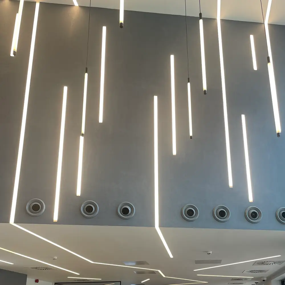 Modern ceiling with vertical and angular linear LED lights and circular air vents.