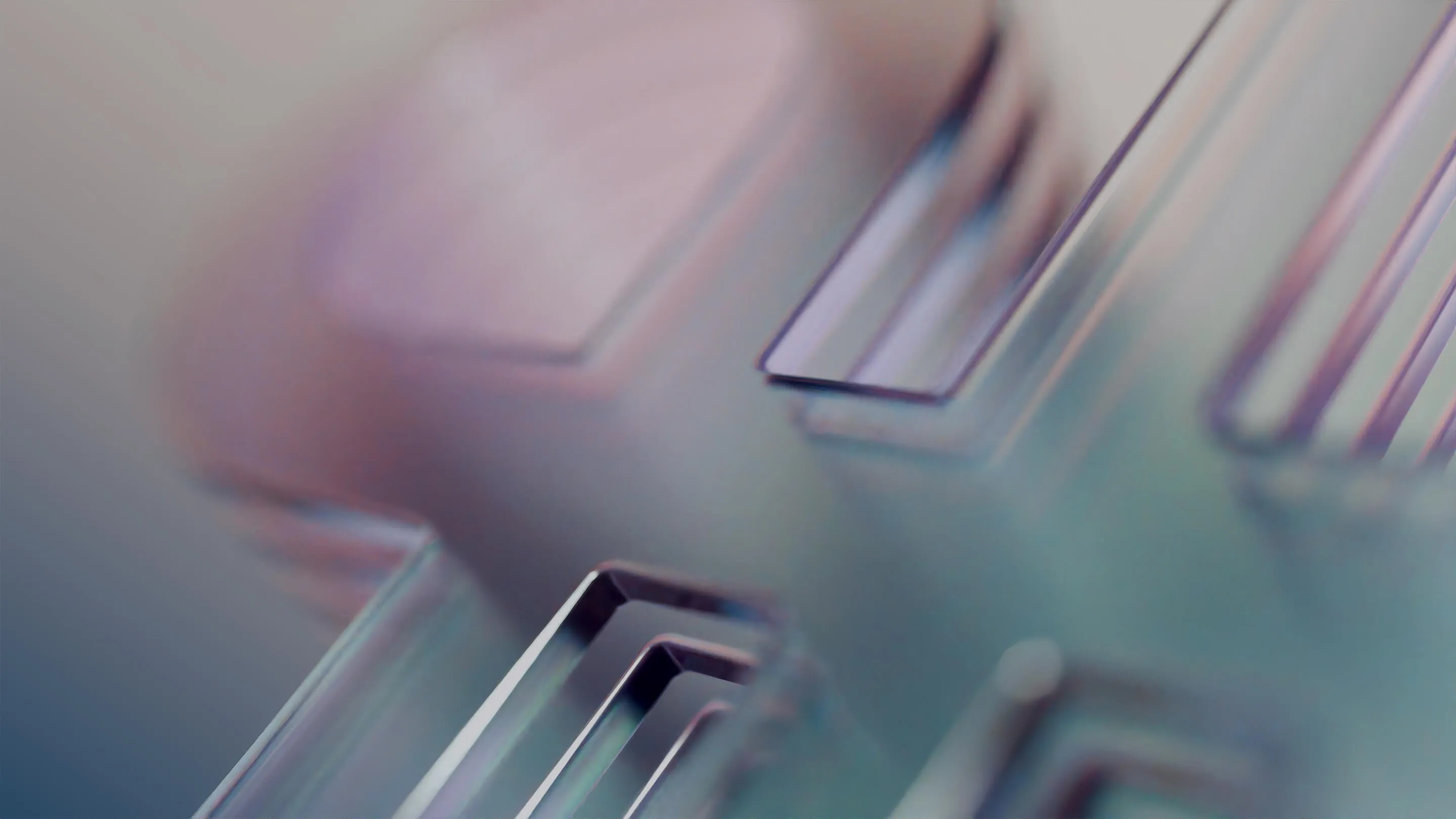 Close-up of a metallic cross-shaped object with smooth, reflective surfaces and blurred edges.