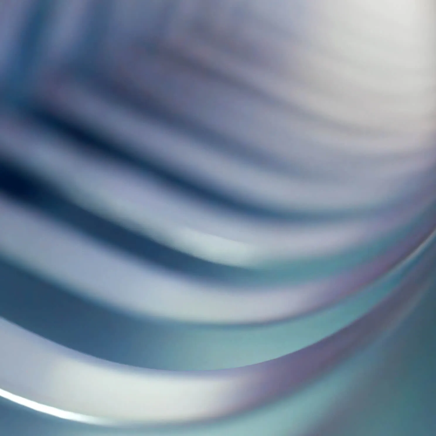 Close-up of smooth, layered metallic or glass surface with reflective, iridescent blue and purple tones.