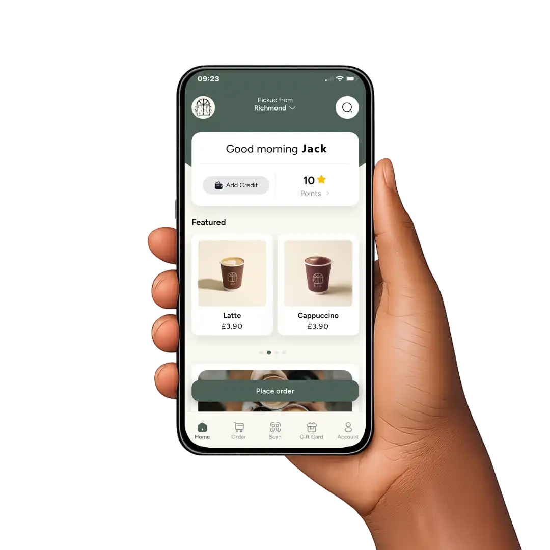 Hand holding smartphone showing coffee app with latte and cappuccino, option to place order.