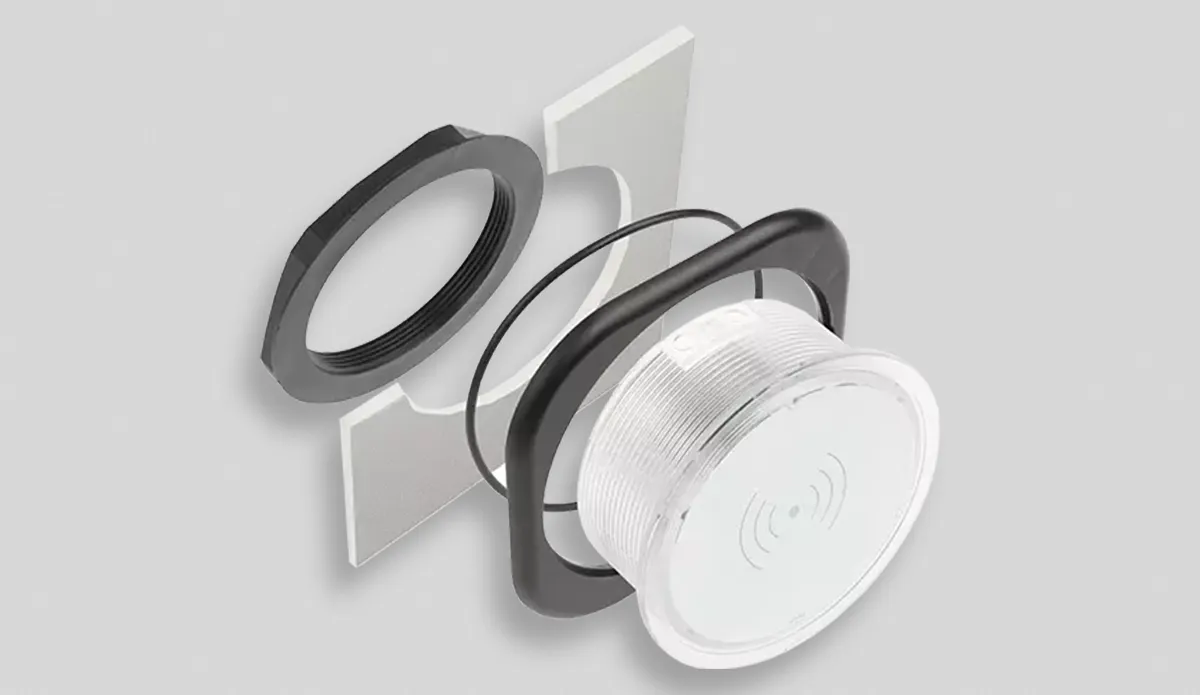 Disassembled compact round panel light showing ring, gasket, mounting plate, and light component.